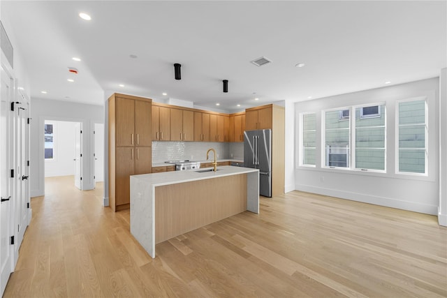 kitchen featuring visible vents, light wood-style flooring, high quality fridge, light countertops, and a sink