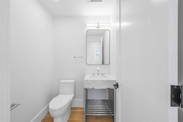 bathroom featuring baseboards, vanity, toilet, and wood finished floors