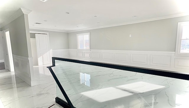 empty room featuring a wainscoted wall, marble finish floor, and crown molding