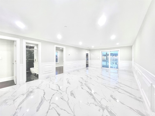 empty room with a decorative wall, recessed lighting, marble finish floor, wainscoting, and crown molding