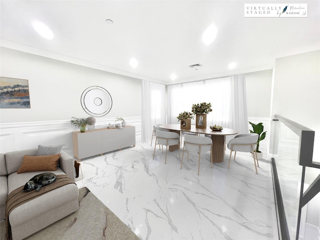 dining area featuring marble finish floor, a decorative wall, and crown molding