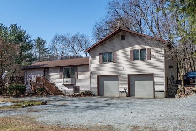 split level home with a garage, driveway, and stairway