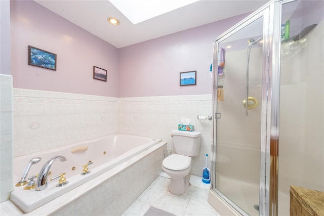 bathroom with toilet, a skylight, tile walls, a shower stall, and tile patterned floors