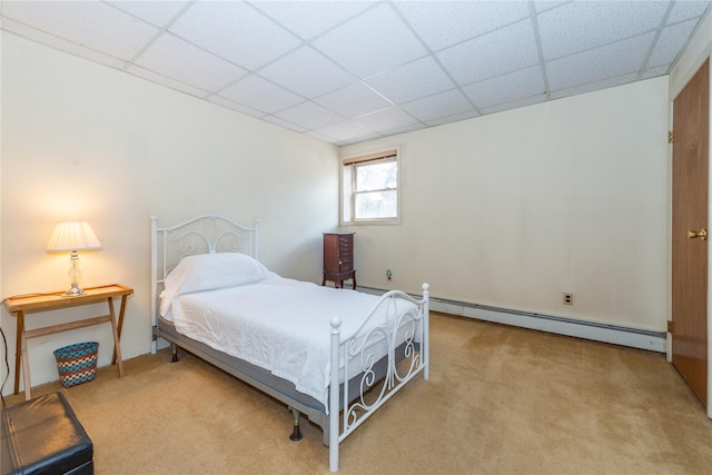 carpeted bedroom with a baseboard radiator and a paneled ceiling