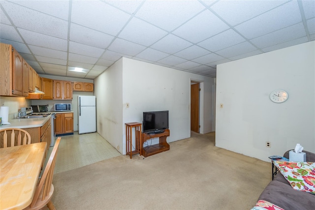 kitchen with a paneled ceiling, light countertops, stainless steel microwave, stove, and freestanding refrigerator