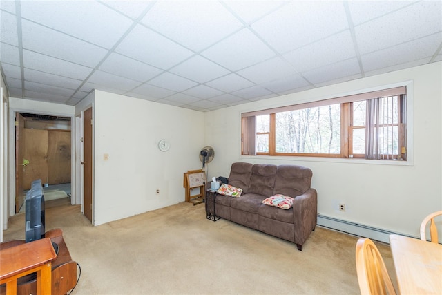 living area featuring light carpet, baseboard heating, and a drop ceiling