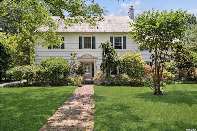 view of front facade with a chimney and a front lawn