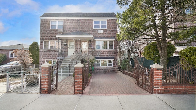 view of front of house featuring a fenced front yard, a gate, brick siding, and decorative driveway