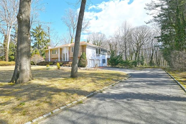 view of front of house with a garage, a chimney, and driveway