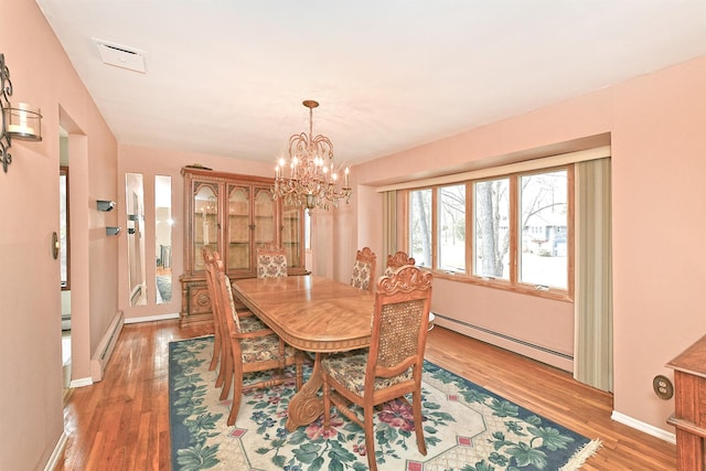 dining area featuring light wood finished floors, baseboards, visible vents, and baseboard heating