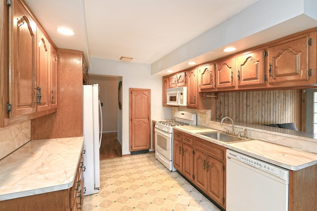 kitchen with white appliances, light floors, a sink, light countertops, and brown cabinets