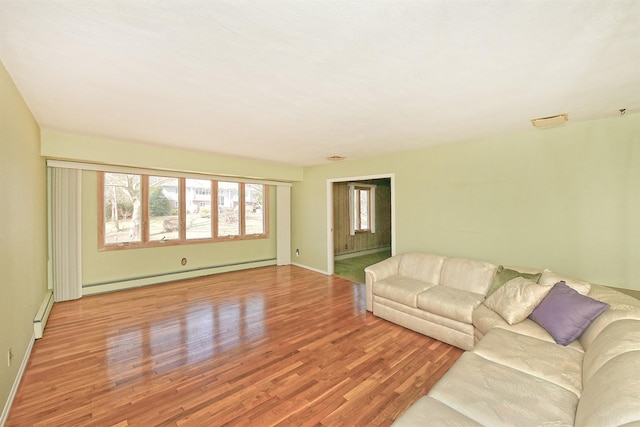 unfurnished living room with baseboard heating and wood finished floors