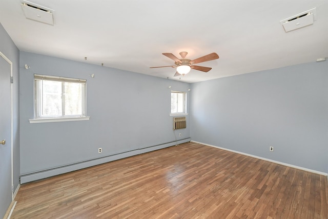 empty room with a baseboard heating unit, wood finished floors, a wall unit AC, baseboards, and ceiling fan