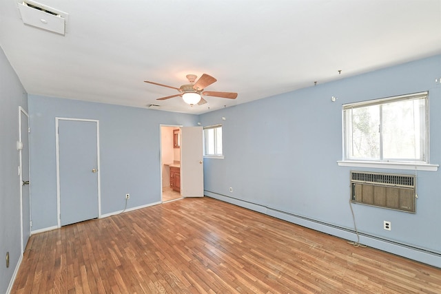 spare room with visible vents, a baseboard heating unit, ceiling fan, a wall mounted air conditioner, and wood finished floors