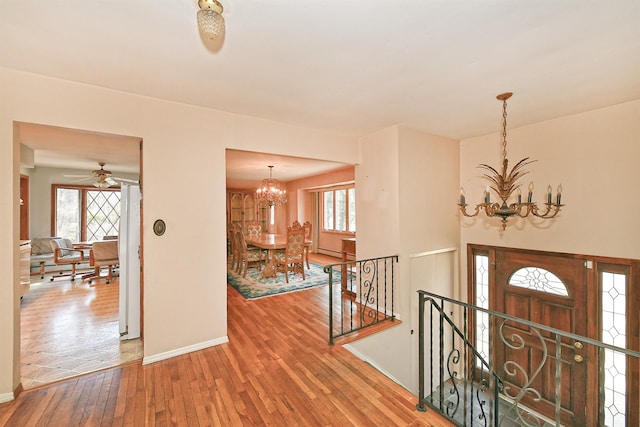 entrance foyer featuring baseboards, an inviting chandelier, and hardwood / wood-style floors