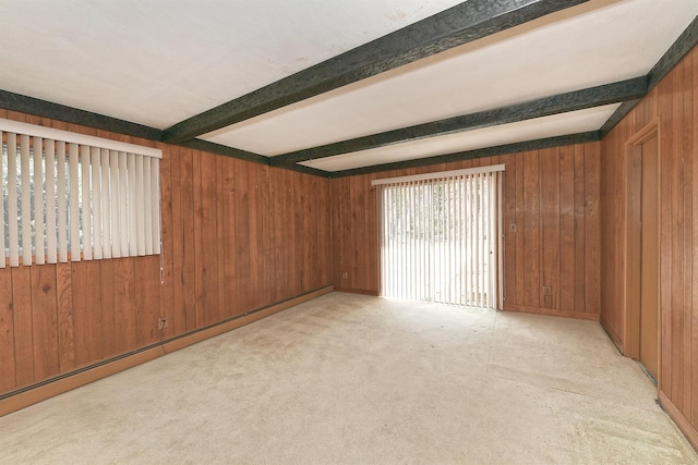 carpeted empty room with a baseboard heating unit, beamed ceiling, and wood walls