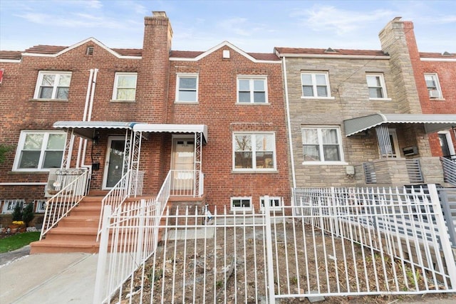 multi unit property featuring a fenced front yard, brick siding, and a chimney