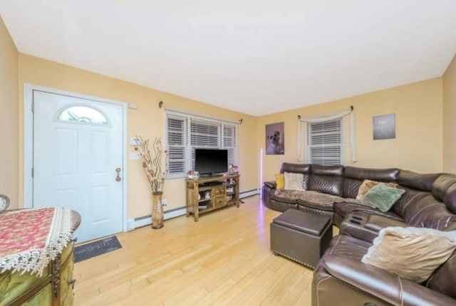 living room with a baseboard heating unit and light wood-style flooring