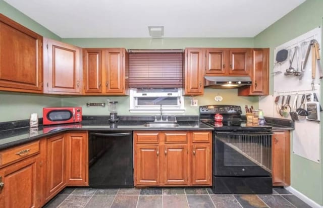 kitchen featuring dark countertops, brown cabinetry, a sink, under cabinet range hood, and black appliances