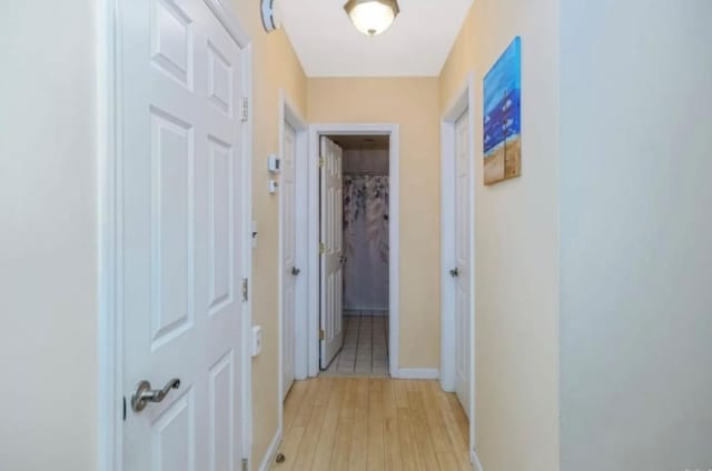 hallway with light wood-type flooring and baseboards