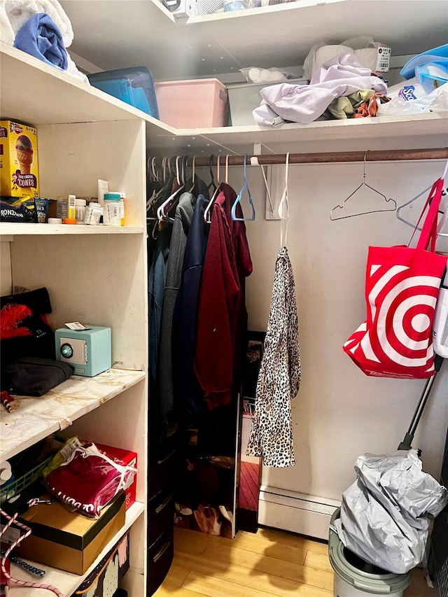 spacious closet with a baseboard radiator and wood finished floors