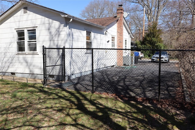 view of side of property with roof with shingles, a chimney, a gate, crawl space, and fence