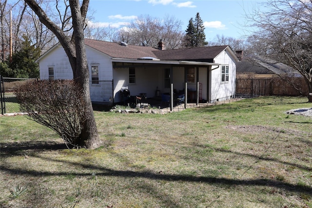 rear view of house featuring a shingled roof, fence, a lawn, a chimney, and a patio area