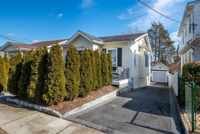 view of home's exterior featuring a garage, an outbuilding, driveway, and fence