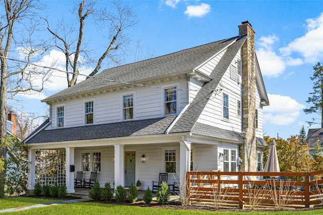 view of front of home featuring covered porch, roof with shingles, and a chimney