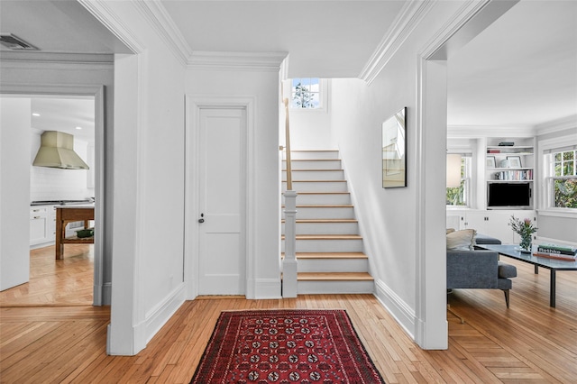 staircase featuring visible vents, baseboards, hardwood / wood-style floors, and crown molding