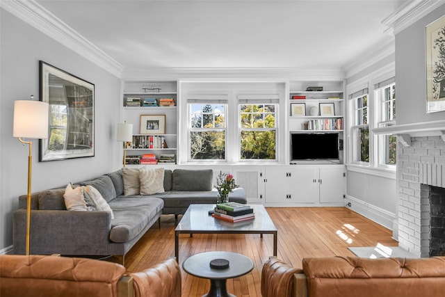 living room featuring a brick fireplace, built in shelves, light wood-style flooring, and ornamental molding