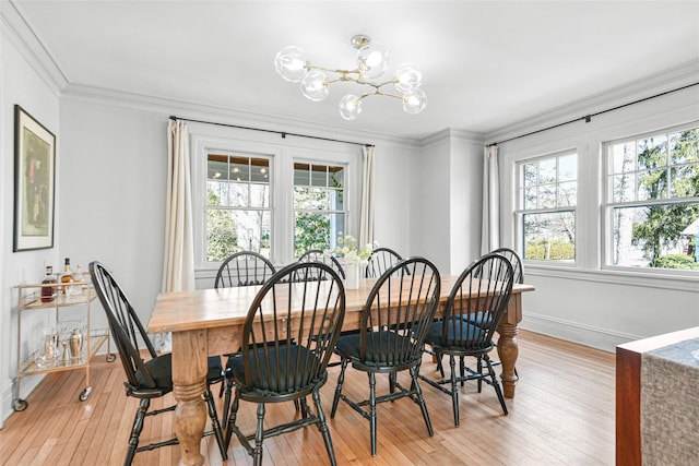 dining space with a notable chandelier, a healthy amount of sunlight, light wood-style floors, and ornamental molding