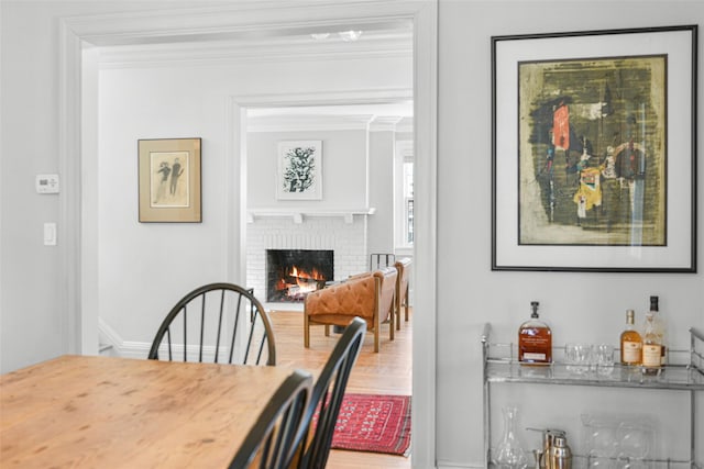 dining area with a fireplace, baseboards, and ornamental molding