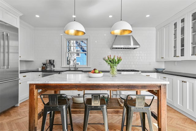 kitchen featuring a sink, stainless steel appliances, backsplash, and wall chimney range hood