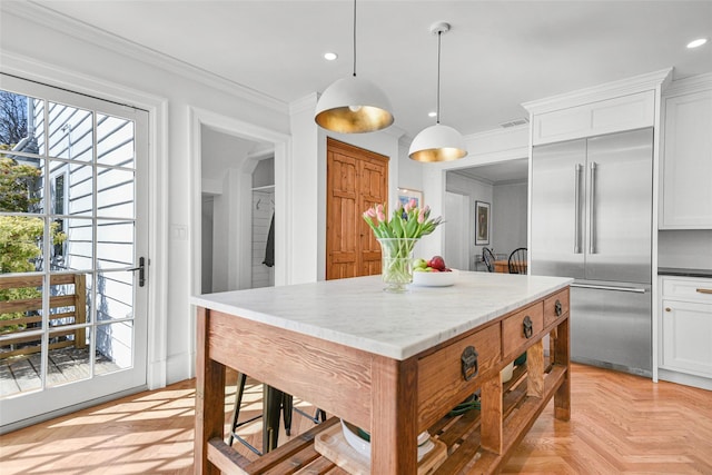 kitchen featuring stainless steel built in refrigerator, ornamental molding, a kitchen island, white cabinetry, and recessed lighting