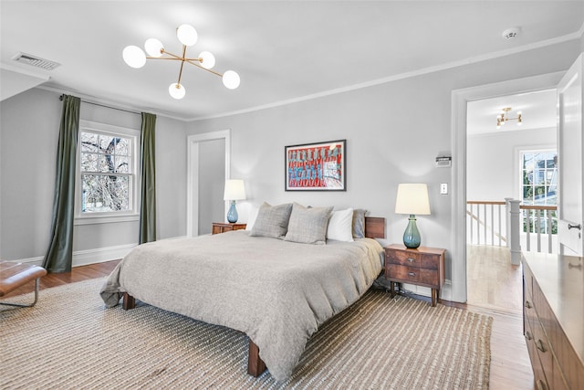 bedroom with light wood-type flooring, visible vents, and ornamental molding