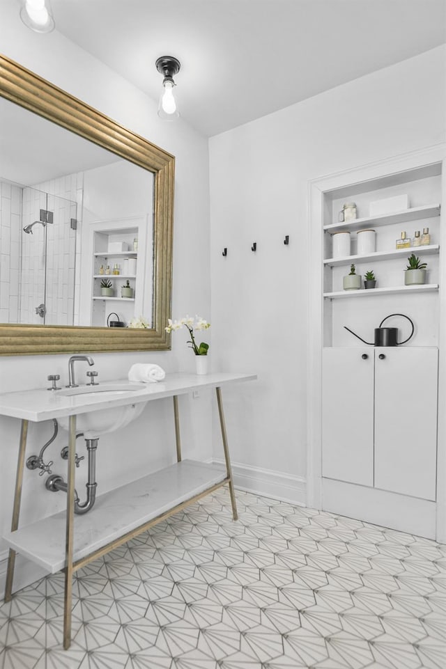 bathroom featuring a tile shower, built in features, and baseboards