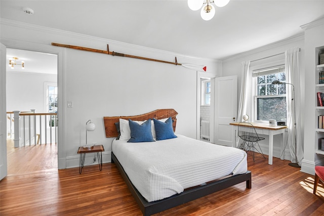 bedroom with crown molding, radiator heating unit, baseboards, and wood-type flooring