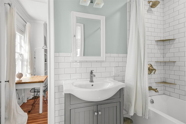 full bath featuring vanity, wood finished floors, a wainscoted wall, shower / bath combo with shower curtain, and tile walls