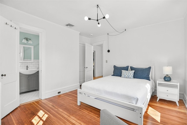 bedroom with light wood-style floors, visible vents, a chandelier, and a sink