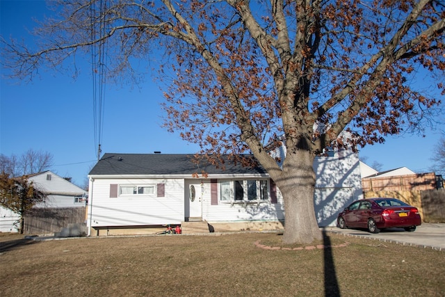 view of front of property featuring entry steps, an attached garage, fence, concrete driveway, and a front lawn