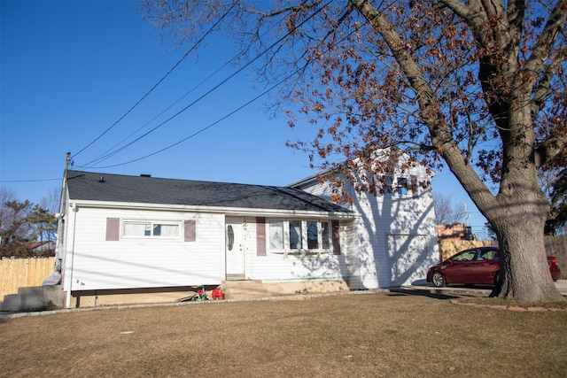 view of front facade featuring entry steps, an attached garage, fence, and a front yard