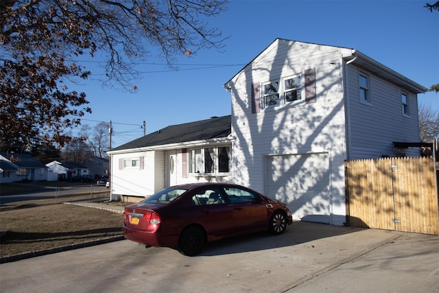 view of home's exterior featuring a garage, fence, and concrete driveway