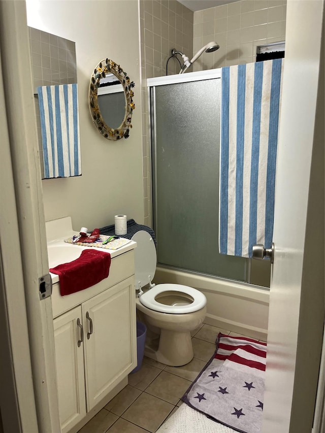 bathroom featuring tile patterned flooring, vanity, toilet, and bath / shower combo with glass door