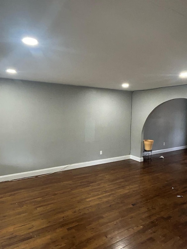 interior space featuring arched walkways, dark wood finished floors, baseboards, and recessed lighting