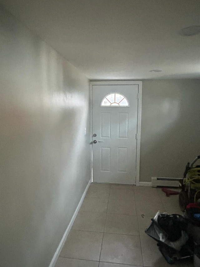 doorway with a baseboard heating unit, baseboards, and light tile patterned floors