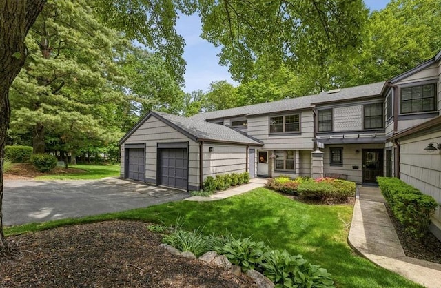 view of front of home featuring a garage, a front lawn, and a shingled roof