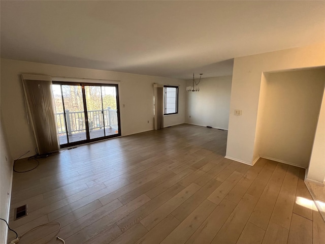 unfurnished room featuring a chandelier, visible vents, and wood finished floors