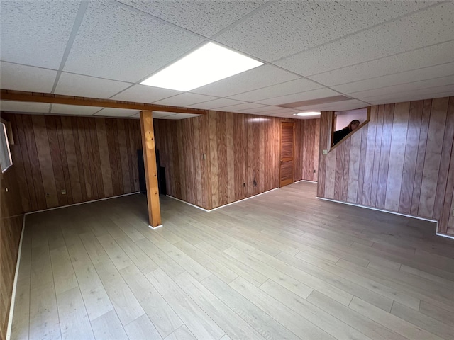 finished below grade area with wood walls, a paneled ceiling, and wood finished floors