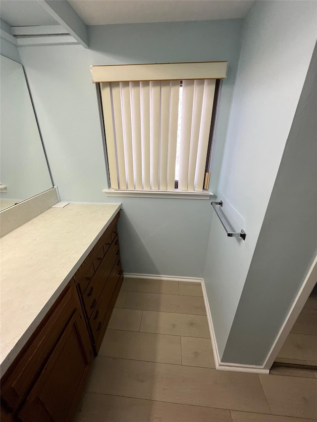 bathroom with baseboards, wood finished floors, and vanity